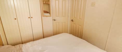 Un dormitorio con cama, armario y puerta con espejo.