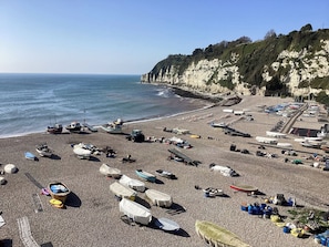 A pebbled beach with boats and a tractor.
