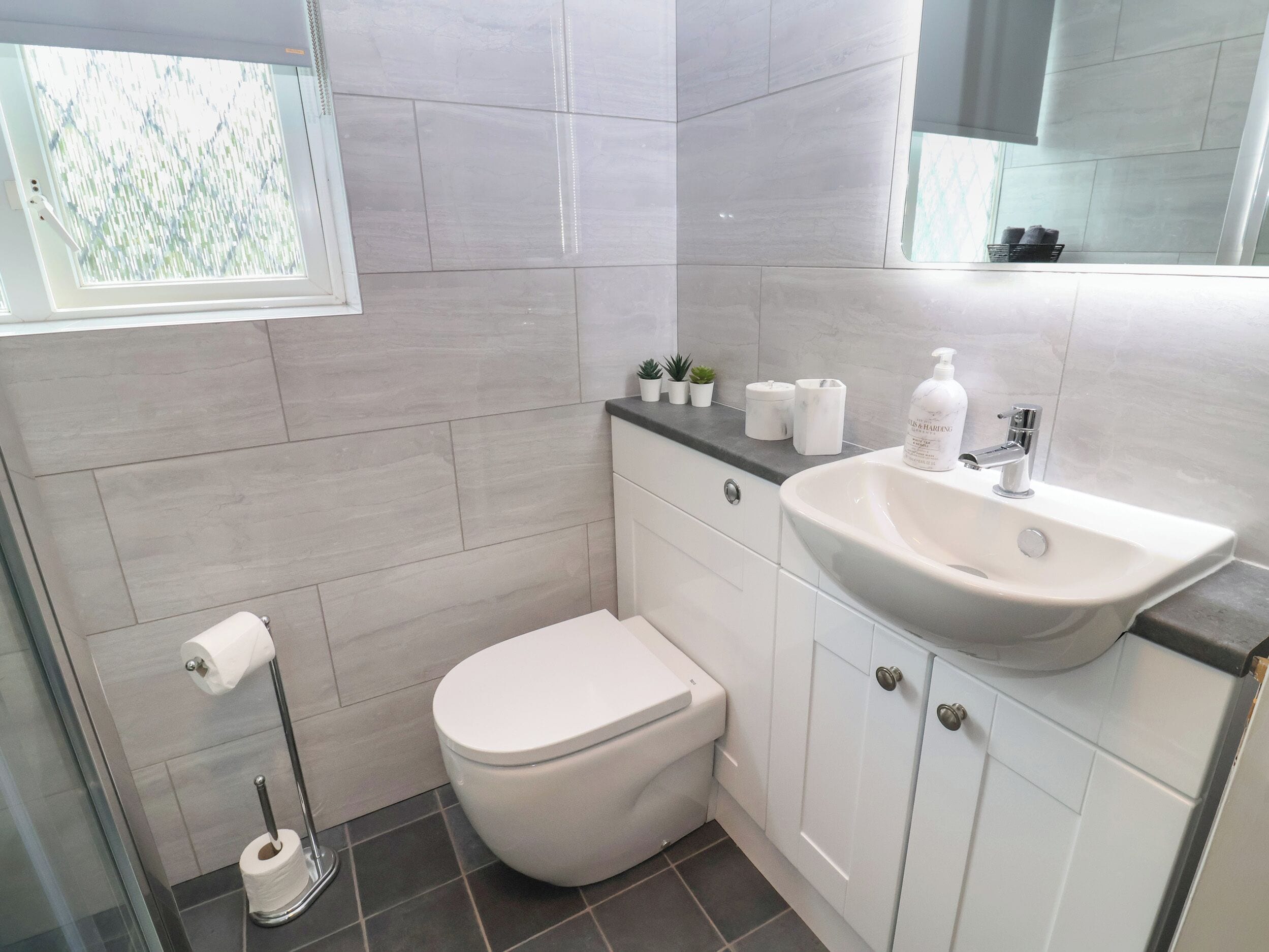 A modern bathroom with a toilet, sink, and a glass shower enclosure.