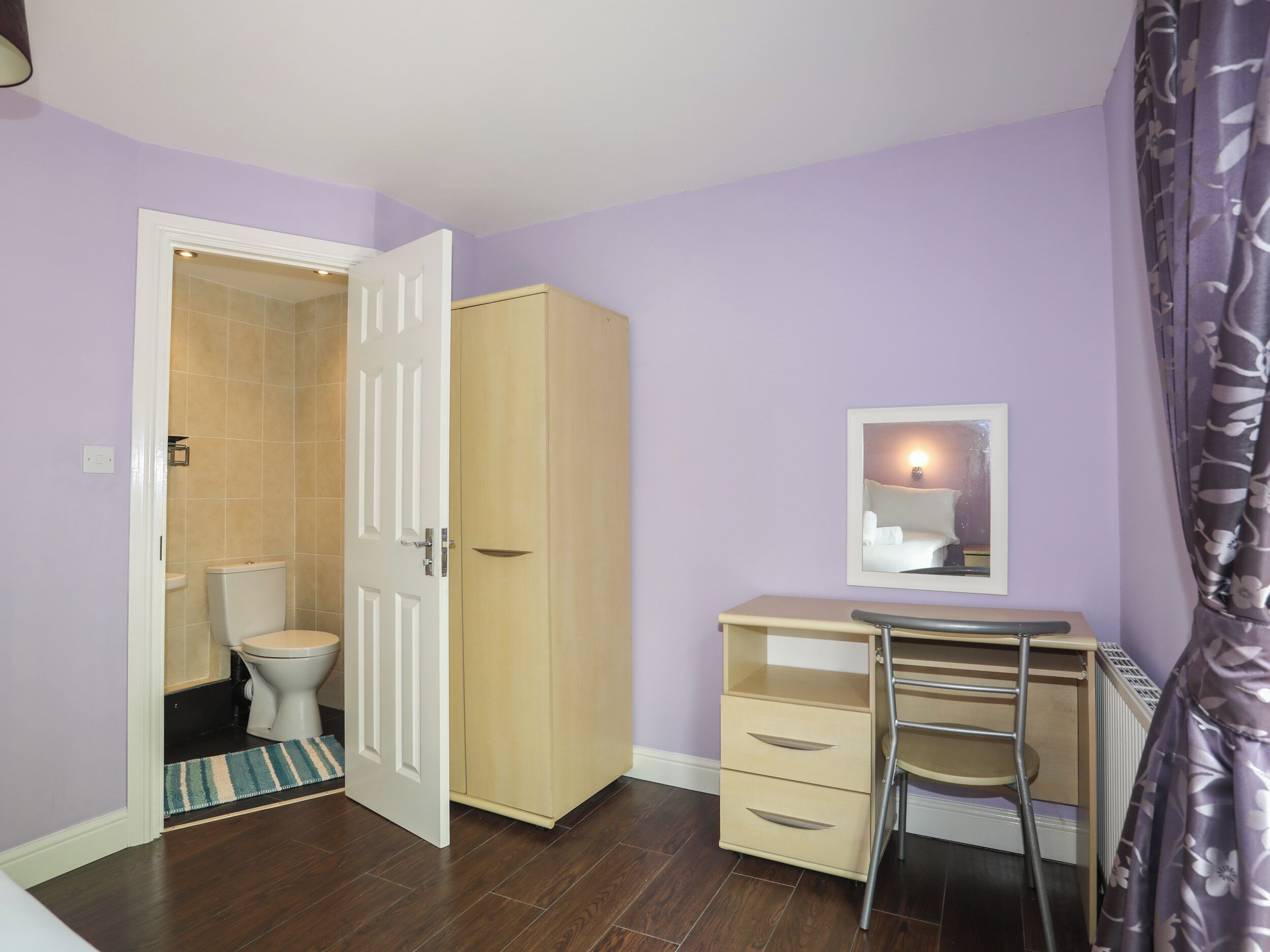A bathroom with a toilet, a cabinet, and a mirror.