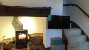 A living room with a fireplace, a television mounted on the wall, and a staircase. - Old Town Cottage (Stratford-upon-Avon)