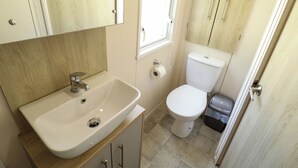A small bathroom with a white sink, toilet, and a window. - The Meadows 45 (Lincoln)