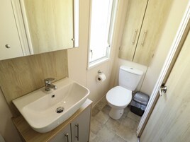 A small bathroom with a white sink, toilet, and a window.