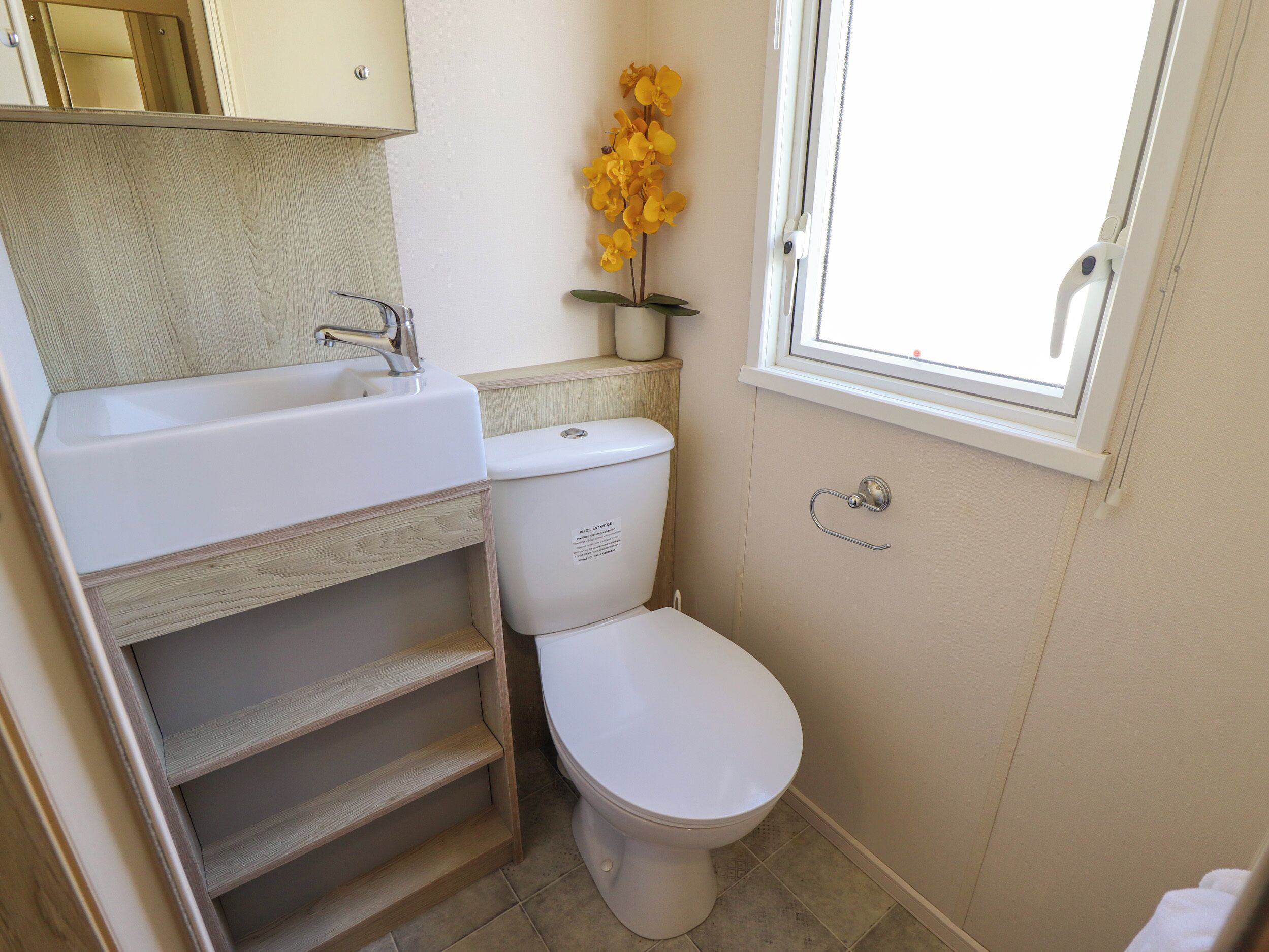 A compact bathroom with a white sink, toilet, and a small window.