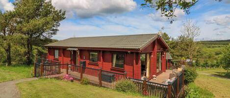 A red building with a porch and a small garden area.