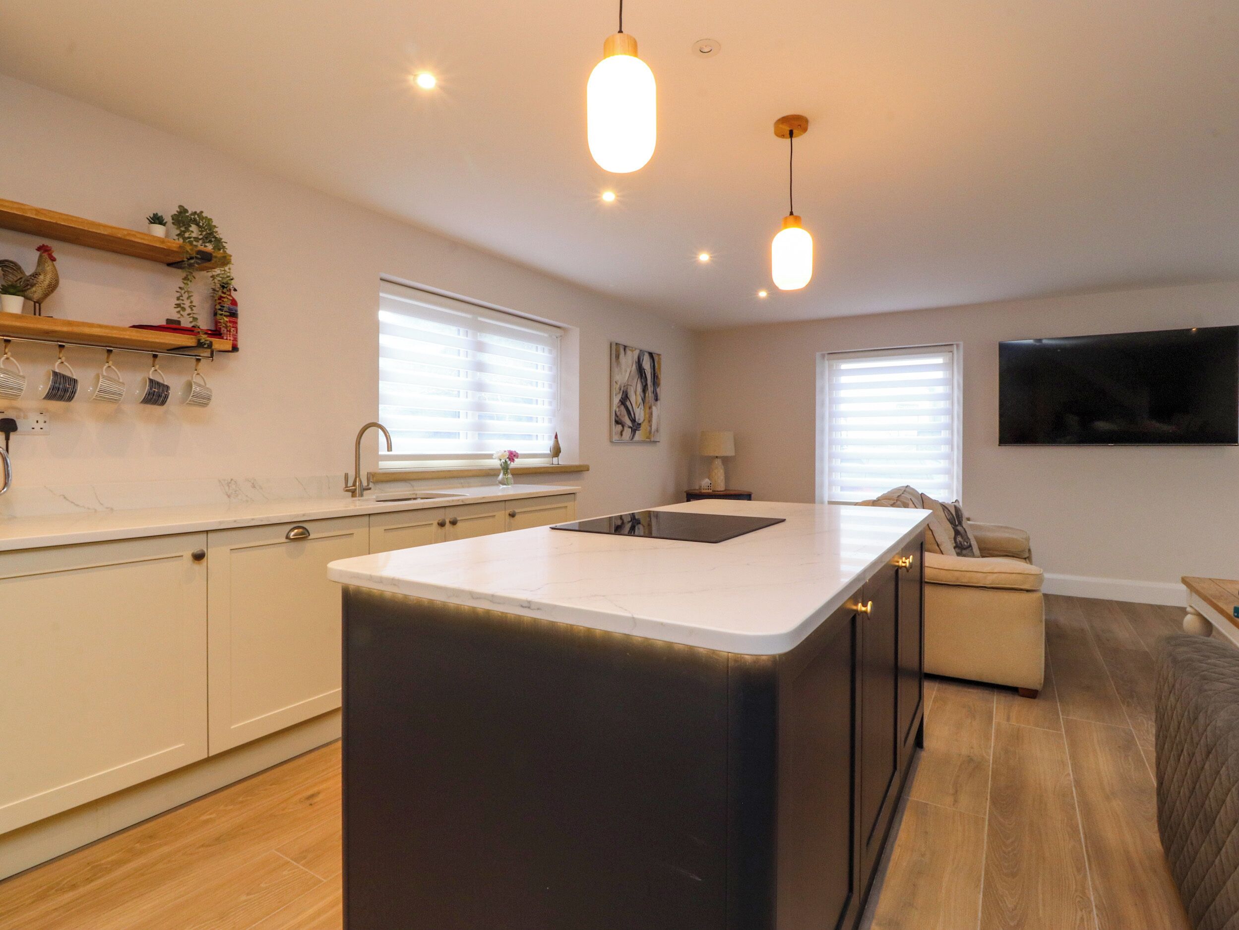 Una cocina moderna con una isla central, suelo de madera e iluminación colgante.