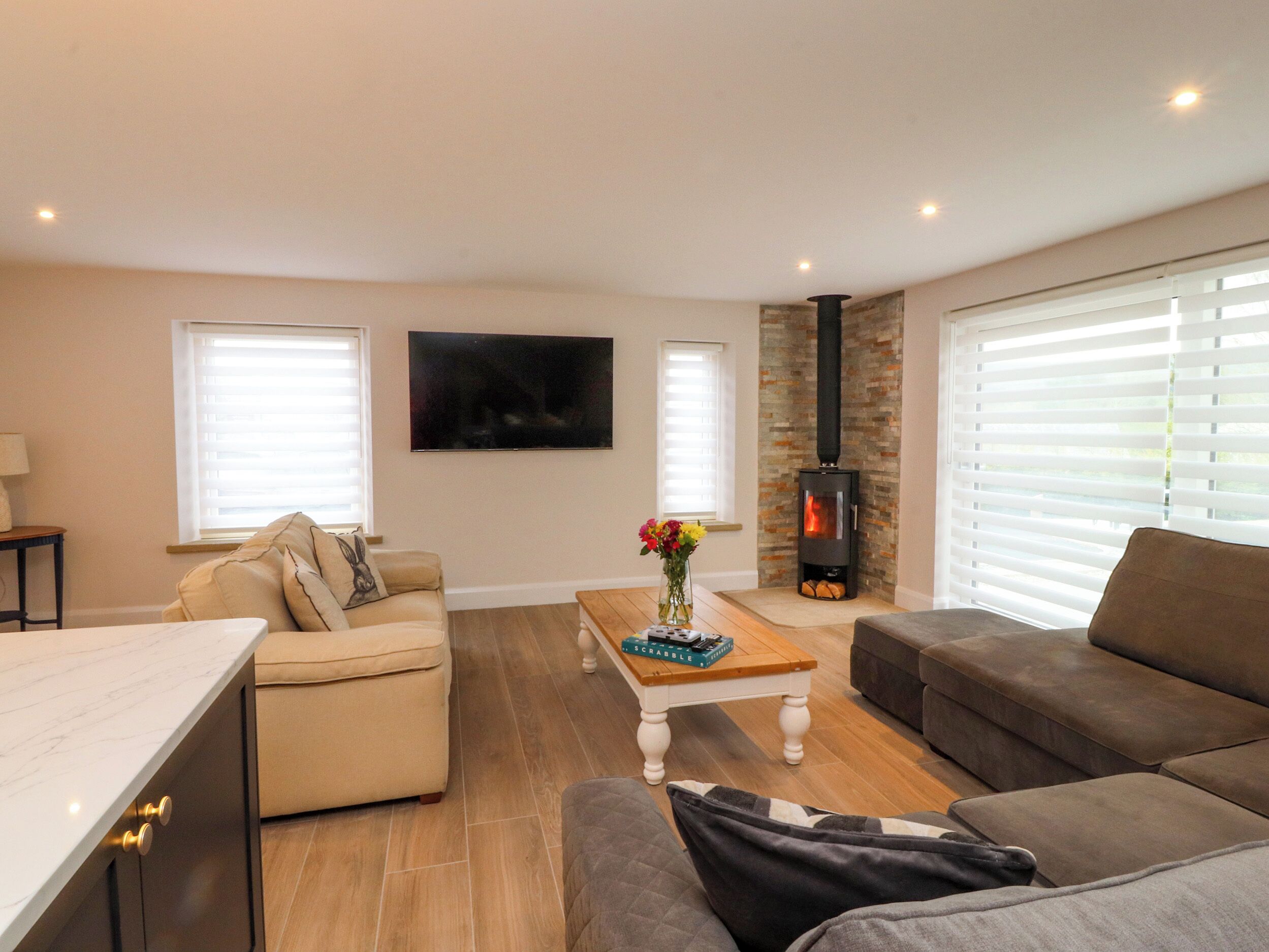 A living room with a fireplace, two sofas, a coffee table, and a TV mounted on the wall.