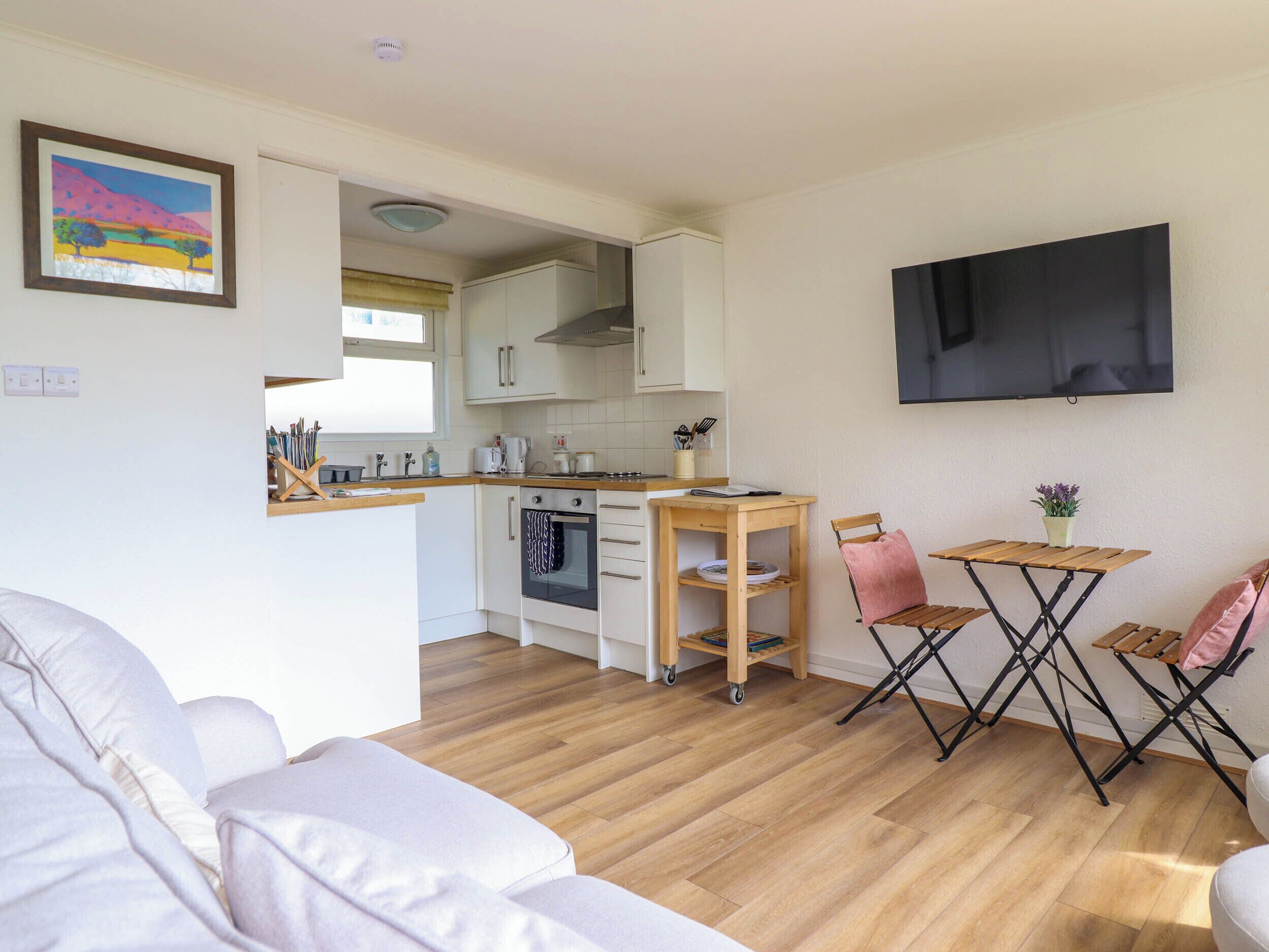 A compact kitchen with white cabinets, a built-in oven, and a wooden dining table.
