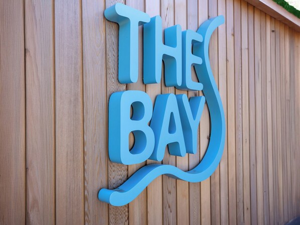 A wooden wall with a blue sign that reads "The Bay". - Lodge 59 at Riviera Bay Coastal Retreat (Brixham)