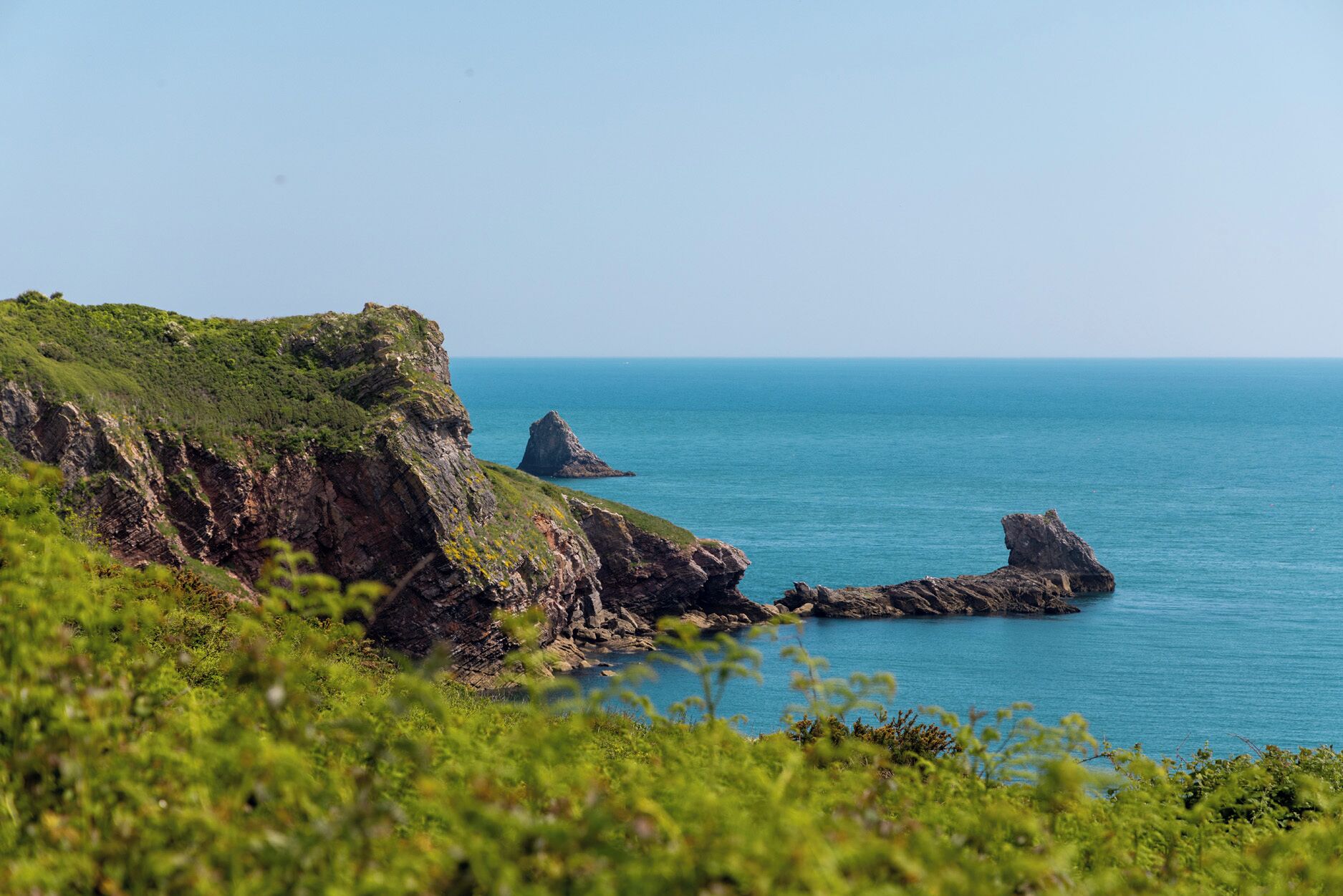 Un paisaje costero con acantilados rocosos y un mar azul cristalino.
