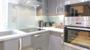 Una cocina moderna con electrodomésticos de acero inoxidable, una placa vitrocerámica y un horno empotrado.