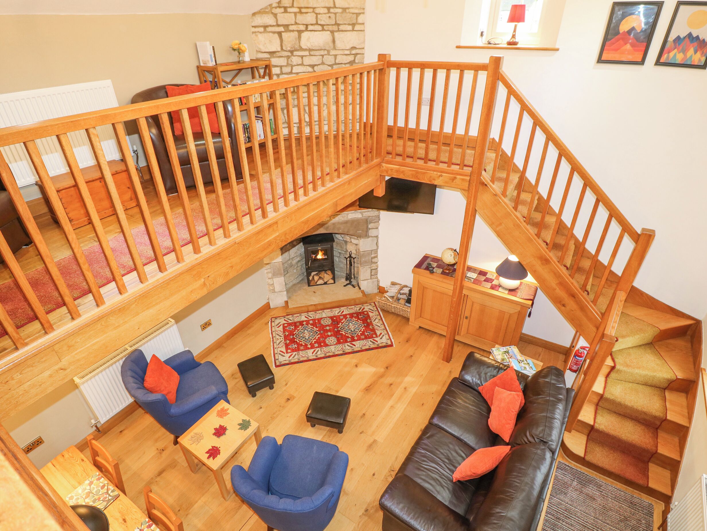 Un vaste espace de vie agrémenté d’un escalier en bois, d’une cheminée, d’un canapé et d’une table basse.