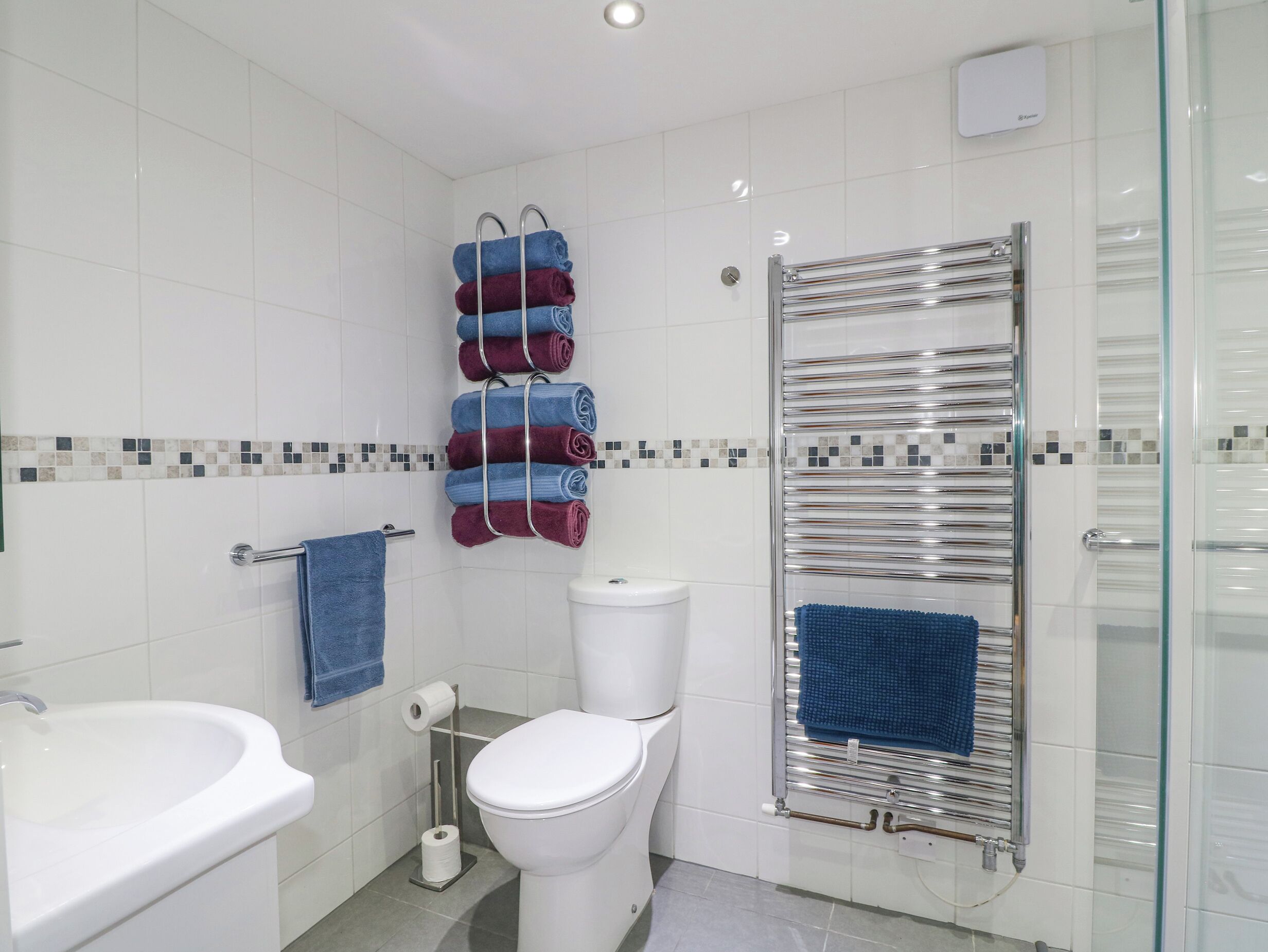 A modern bathroom with a white sink, toilet, and glass shower enclosure.
