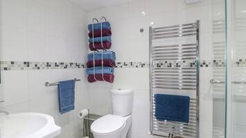 A modern bathroom with a white sink, toilet, and glass shower enclosure.