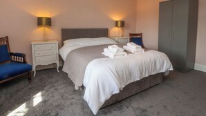 Una camera da letto ordinata con un letto grande, due comodini con lampade, un armadio e una sedia.