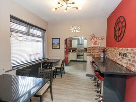 A restaurant with a dining area, kitchen, and a red accent wall.