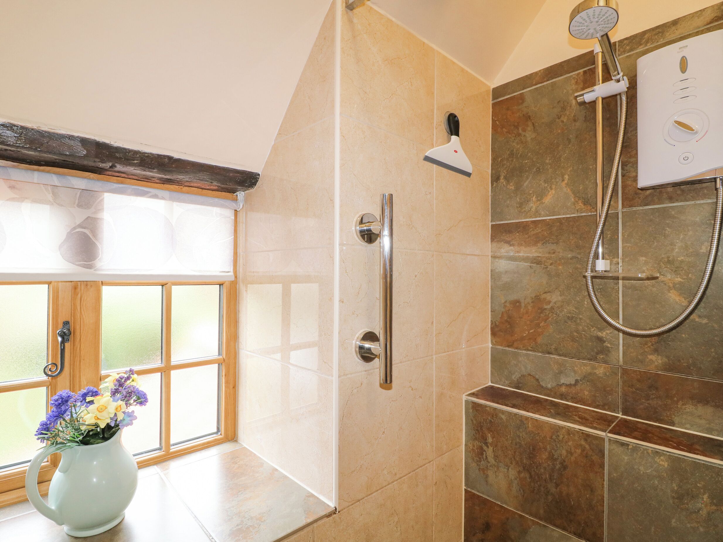 A bathroom with a shower, a toilet, and a window with a view.