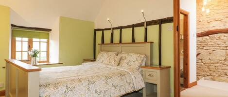 A bedroom with a bed, nightstands, a window, and a stone wall.
