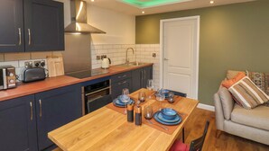 A modern kitchen with dark cabinets, a wooden countertop, and a dining area with a table set for two. - Picadore Two (Scarborough)