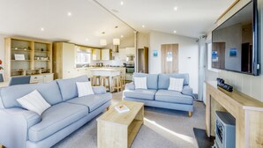 Un salon moderne avec deux canapés bleu clair, une table basse en bois et un téléviseur posé sur un meuble en bois.