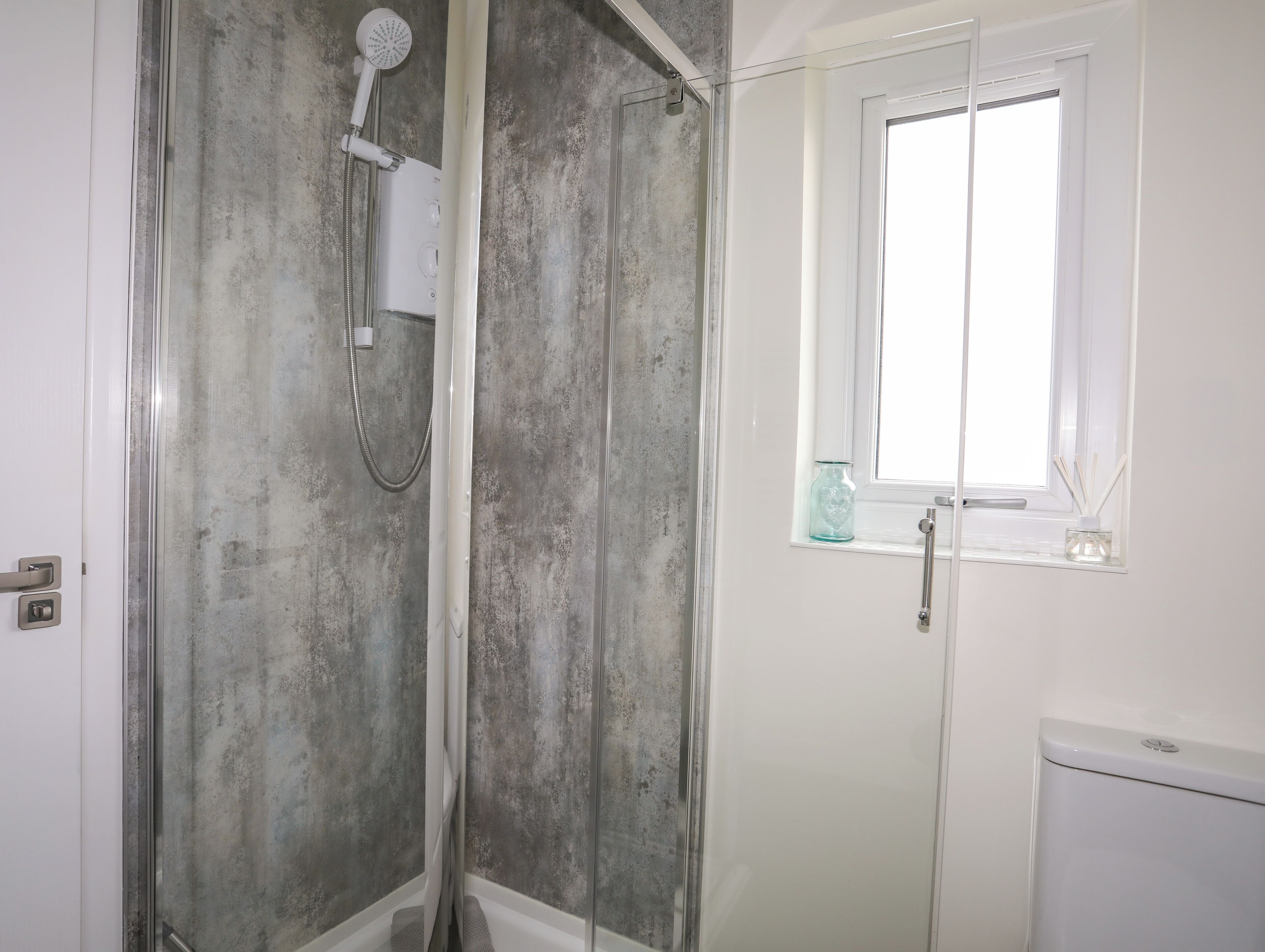 Une salle de bain avec une douche, une fenêtre et des toilettes.