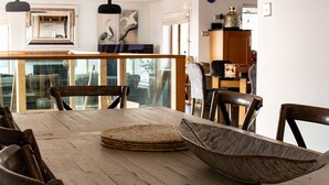 A dining area with a wooden table, woven placemats, and wooden chairs. - Swyn Llyr (Rhosneigr)