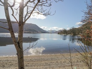 A serene lake with a clear sky, surrounded by mountains and trees. - Ullswater View Apartment (Penrith)