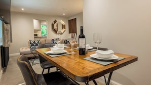 Un comedor con una mesa de madera, platos blancos, copas de vino y una botella de vino.
