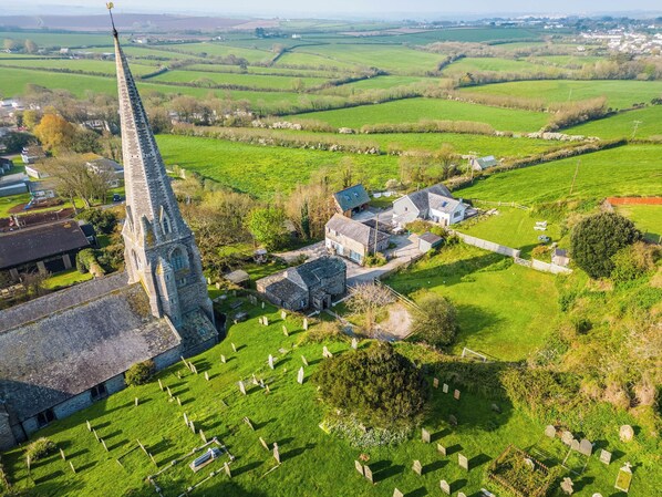 Une église dotée d’un clocher imposant, un cimetière et des champs verdoyants environnants.