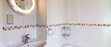 Une salle de bain avec un lavabo blanc, un miroir avec un cadre en bois et une baignoire.