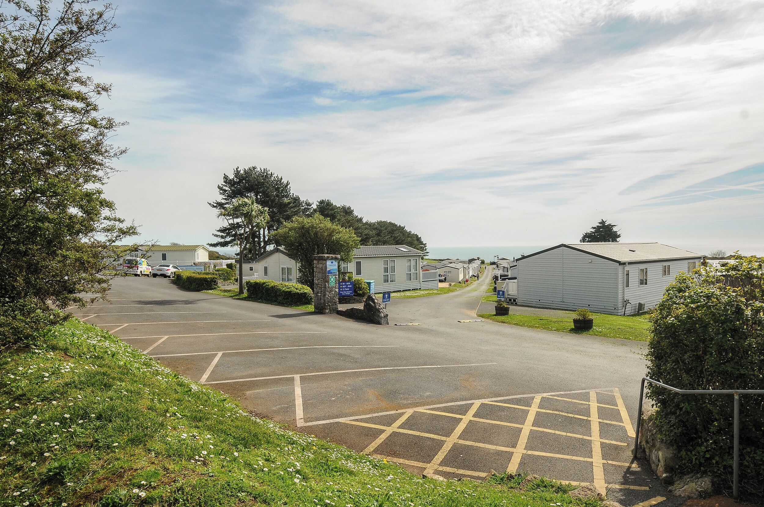 A parking lot with caravan-style buildings, a clear sky, and a grassy area with a hedge.