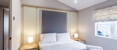 Ein Hotelzimmer mit einem Bett, zwei Nachttischen, einem Fenster mit Blick und einer Tür.