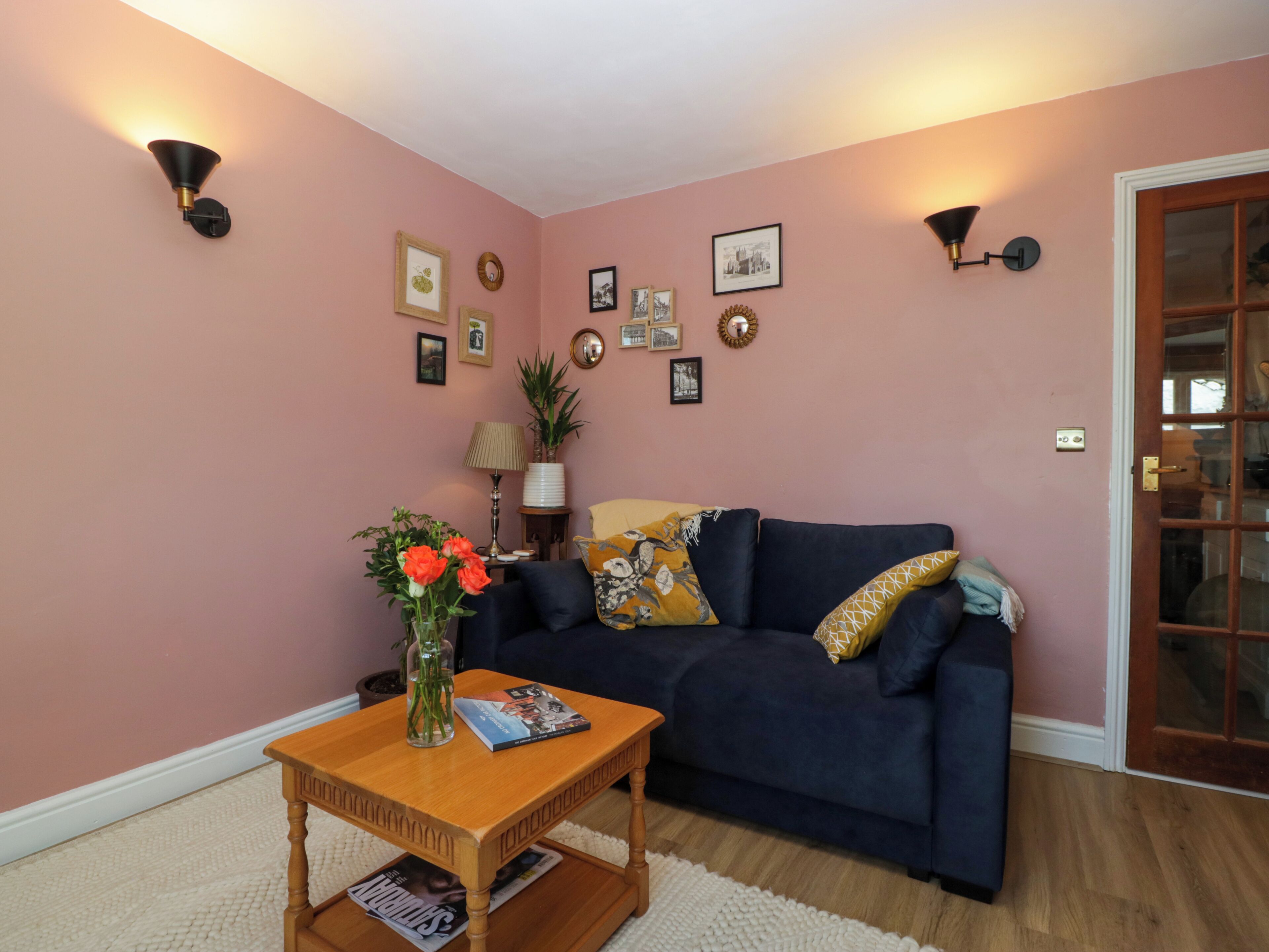 A living room with a dark blue sofa, a wooden coffee table, and a vase with flowers.