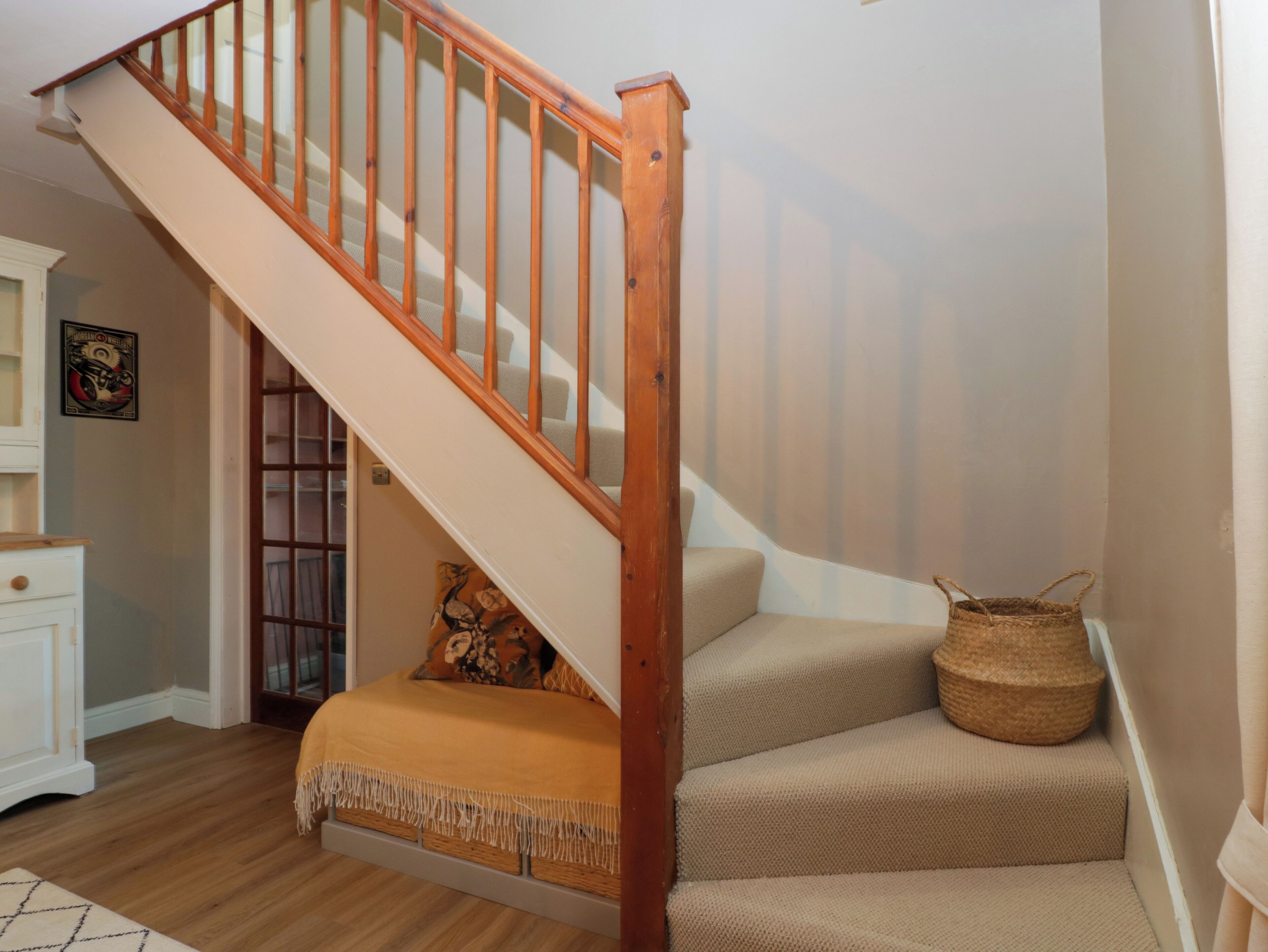 A staircase with wooden railings and beige carpeted steps.