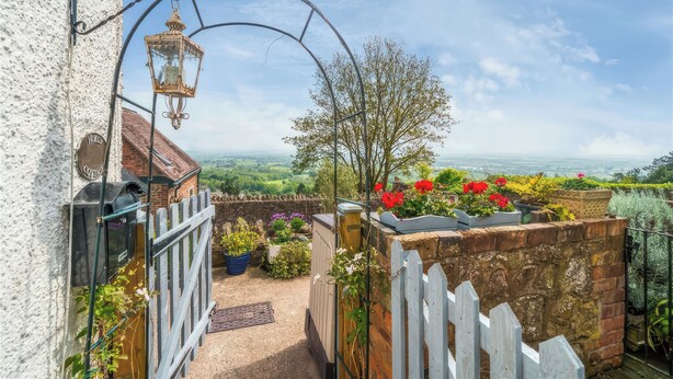 Ein Garten mit weißem Zaun, einer Laterne und Blick auf die Landschaft.