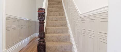 A staircase with a wooden handrail and a carpeted landing.