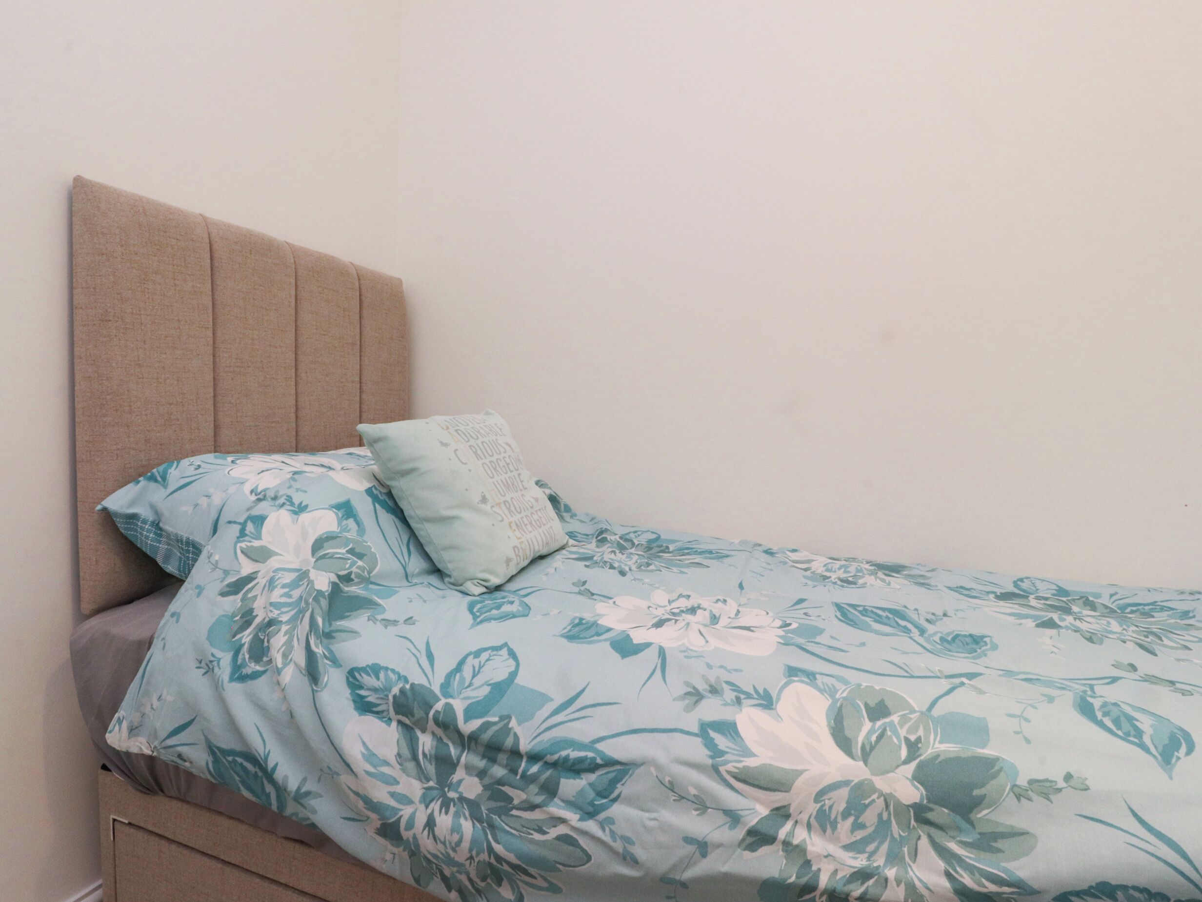 Ein Bett mit einem blumigen Überwurf und einem Kopfteil.