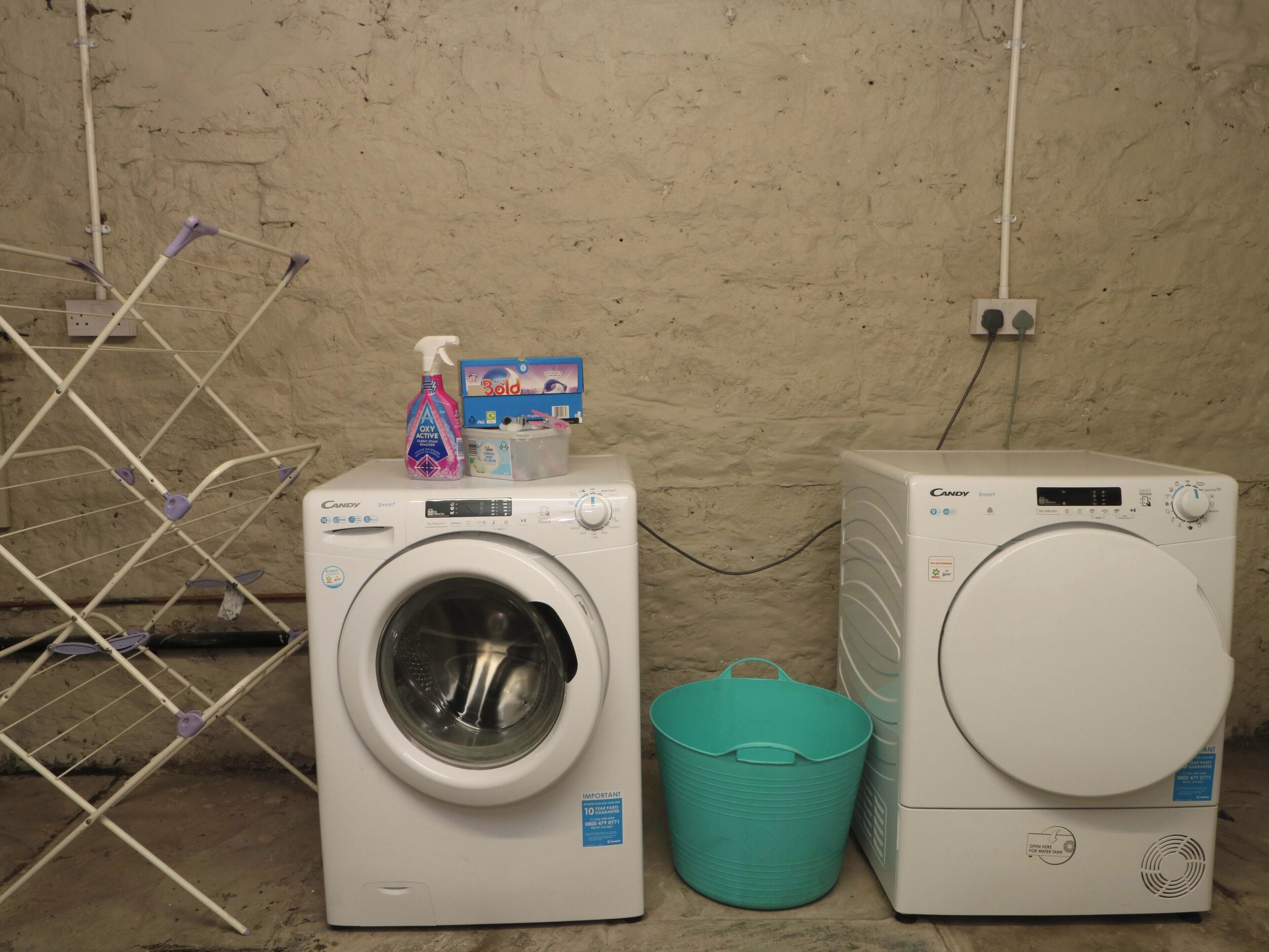 Un espace dédié à la lessive, comprenant un lave-linge et un sèche-linge à chargement frontal, un étendoir et un seau.
