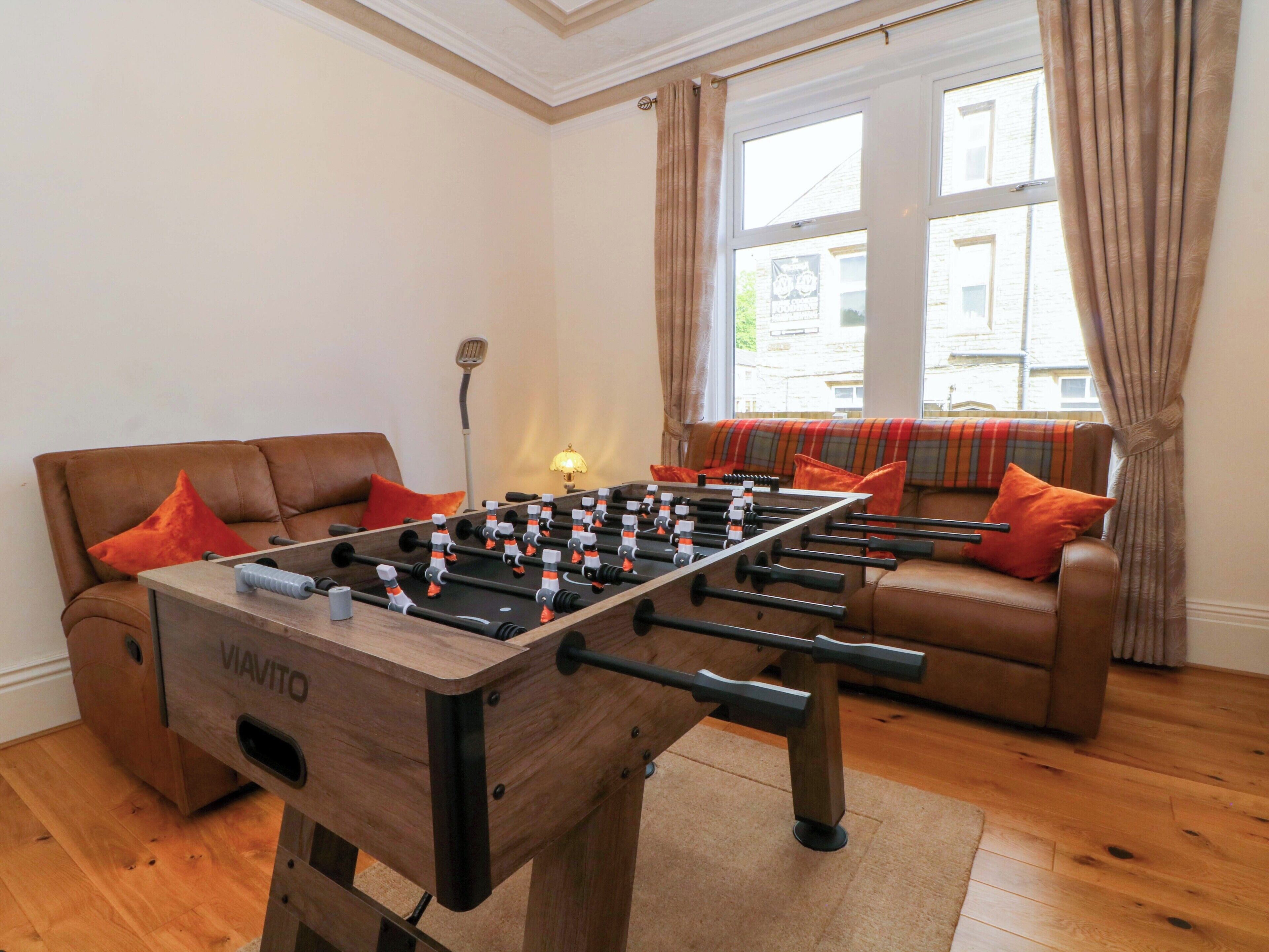 Huone, jossa on pöytäjalkapallopeli, sohva ja lamppu.
