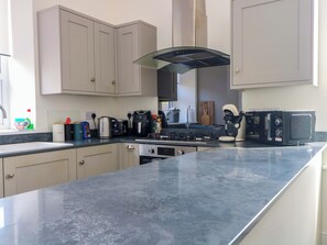 A modern kitchen with a gas stove, coffee maker, toaster, and microwave. - 163 Manchester Road (Accrington)