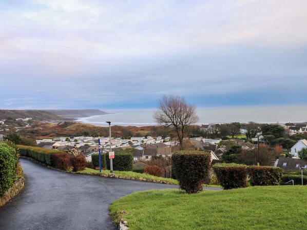A coastal road with houses, a clear sky, and a view of the sea. - Chalet 27 (Swansea)