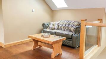 Una habitación acogedora con una mesa de madera, un sofá con cojines y un ventanal de vidrio.