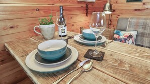 Une table en bois, dressée avec des assiettes bleues et blanches, une bouteille de vin, un verre, une cuillère et une petite plante en pot.
