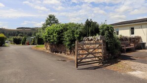 A rural road leading to a stone gate, a stone wall, and a building with a window. - Stable Cottage (Newcastle-upon-Tyne)