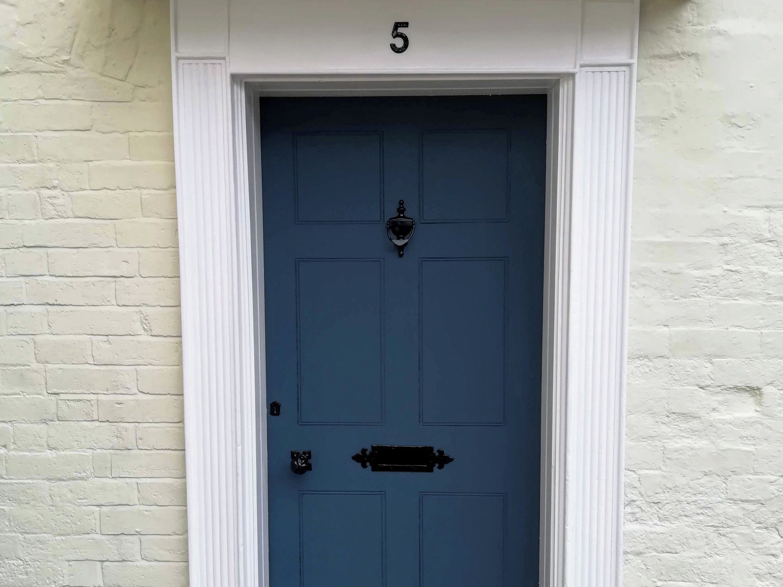 A blue door with a white frame and a number '5' above it.