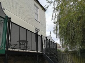 A white building with a black metal fence and stairs leading to a balcony. - River Cottage (Derby)