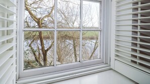 A window with a view of bare trees and a body of water. - River Cottage (Derby)