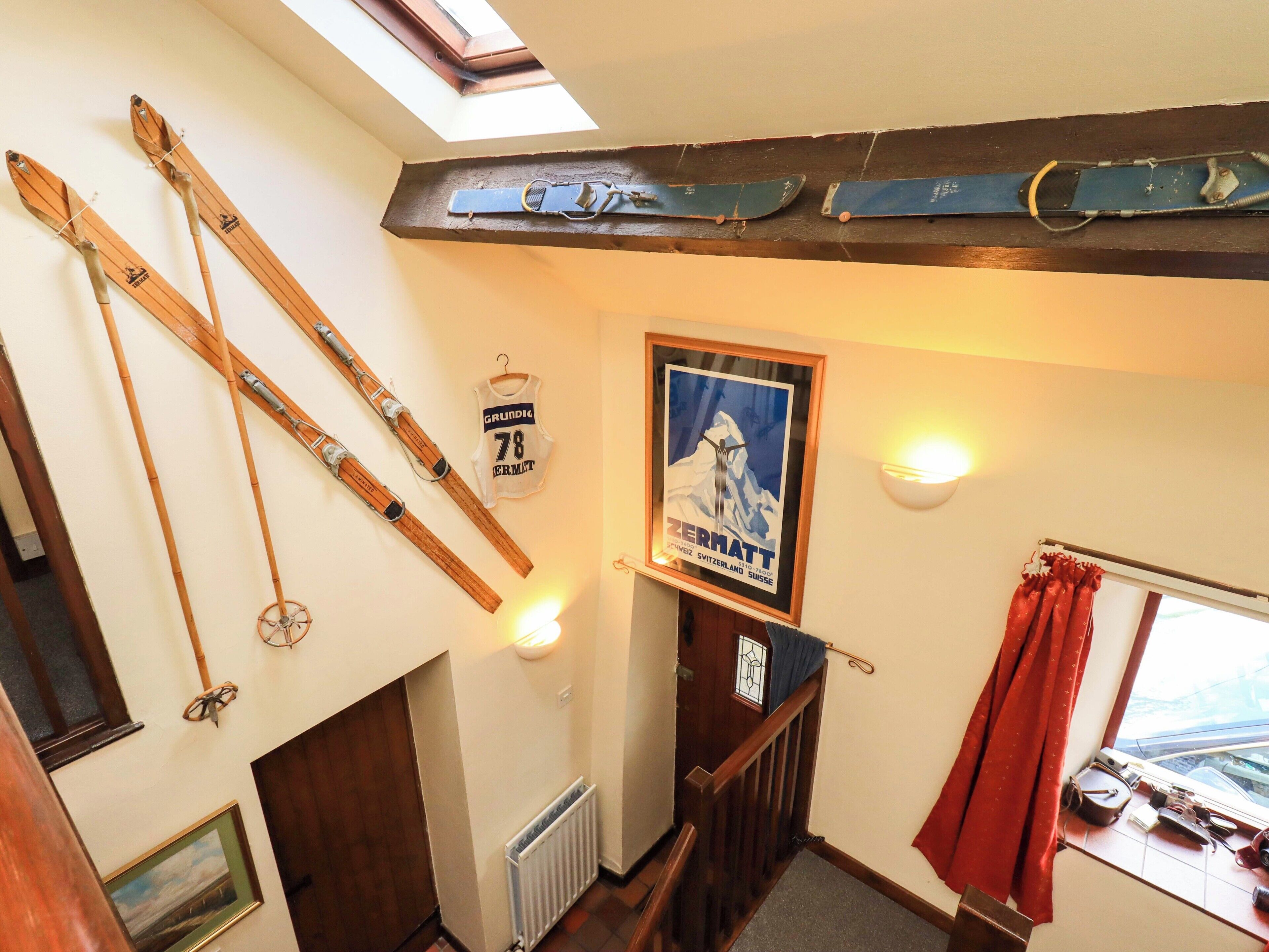 Quarto com esquis de madeira, um quadro, um radiador e uma janela com vista.