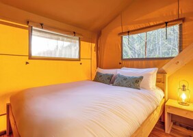 Un dormitorio acogedor con una cama grande, dos ventanas y techo de madera.