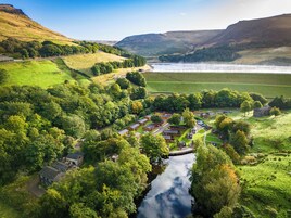 A rural village with a river, surrounded by hills and greenery.